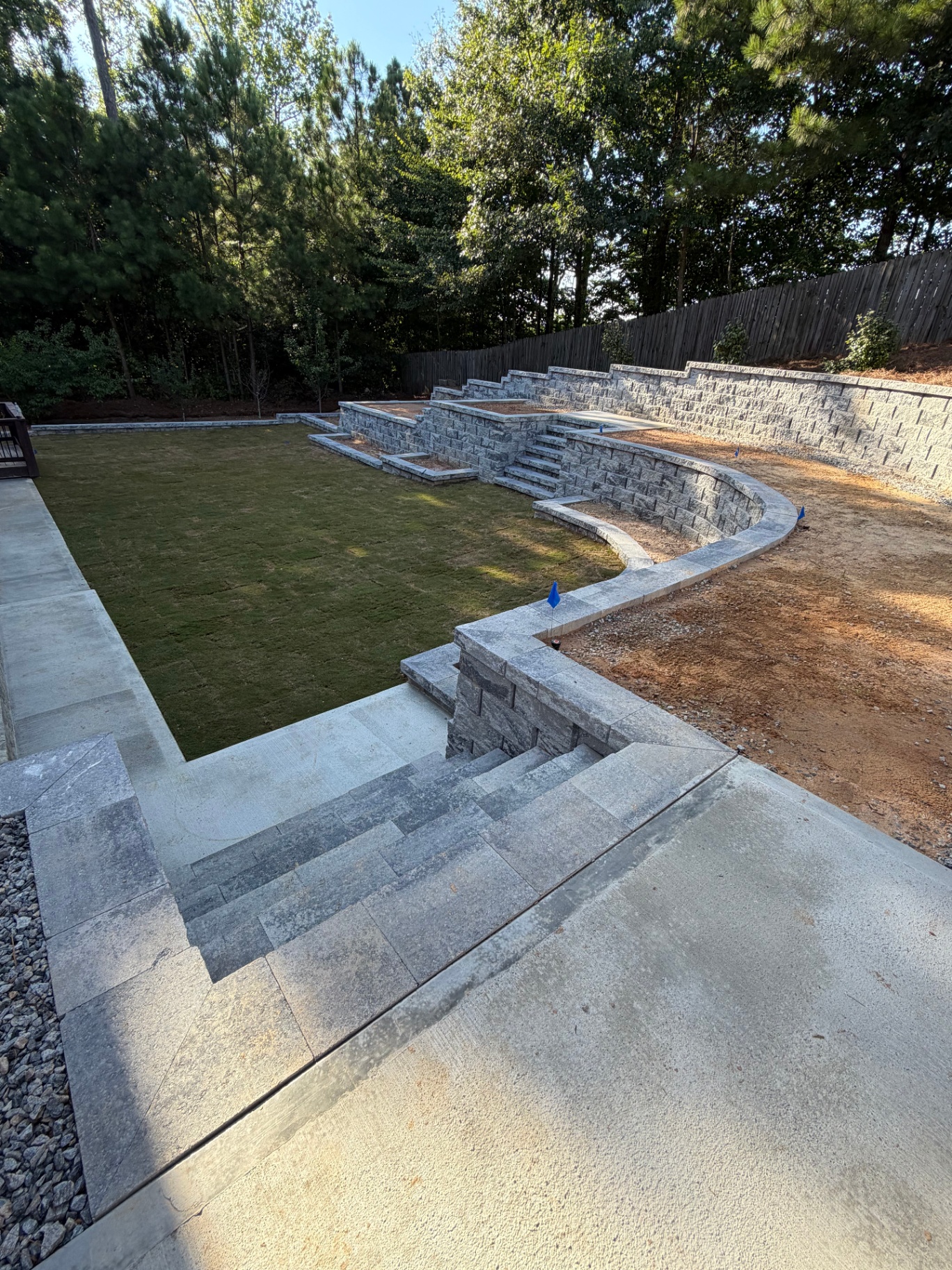M&M Outdoor Solutions curved retaining walls, stone steps and backyard lawn